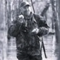 a close-up of a man in the swamp holding some animal with right hand, he's hunting